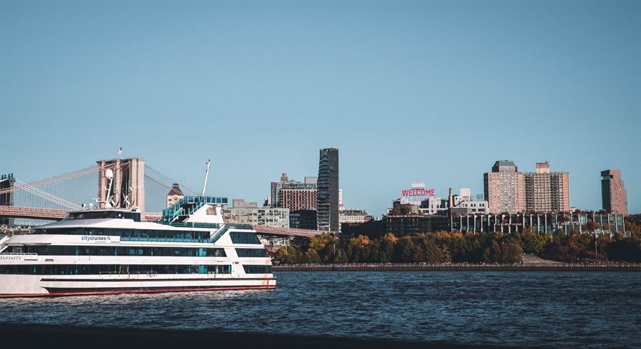White harbor cruise boat on the East River with the Brooklyn Bridge and Manhattan behind
